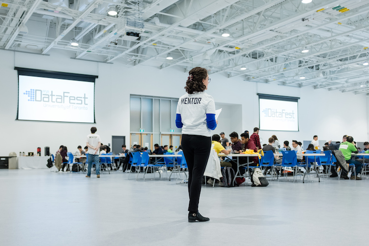 Mentor standing in front of tables with students