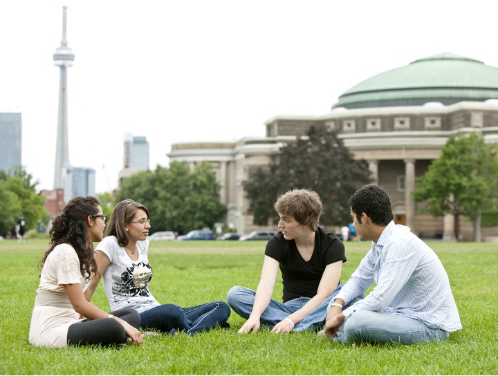Students sitting on grass in front of Convocation Hall