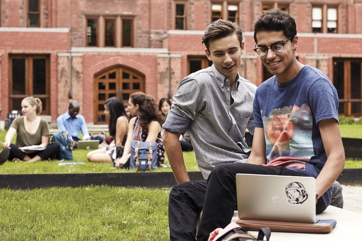 Two students working together looking at a laptop