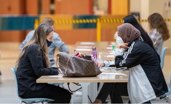 Two students with masks sitting at table working