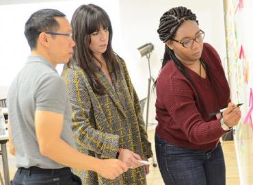 3 people standing in front of a board